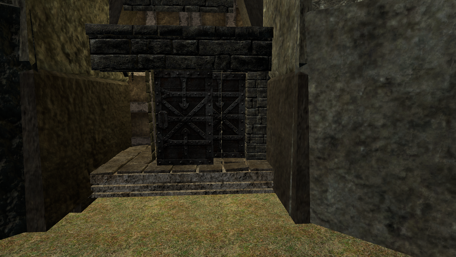 Stone gatehouse entrance of Hilt Fortress with a single dark metal double door at the top of grass steps